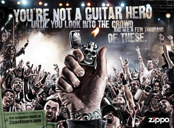 A zippo lighter is held up in front of a massive crowd of ravenous fans at a rock concert