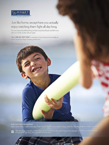 A young boy sports a funny facial expression while playing tug of war with an older sibling at a beach