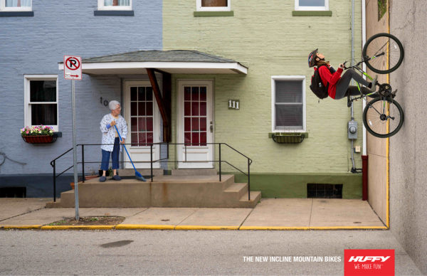 A bicyclist climbs a vertical road in an urban setting